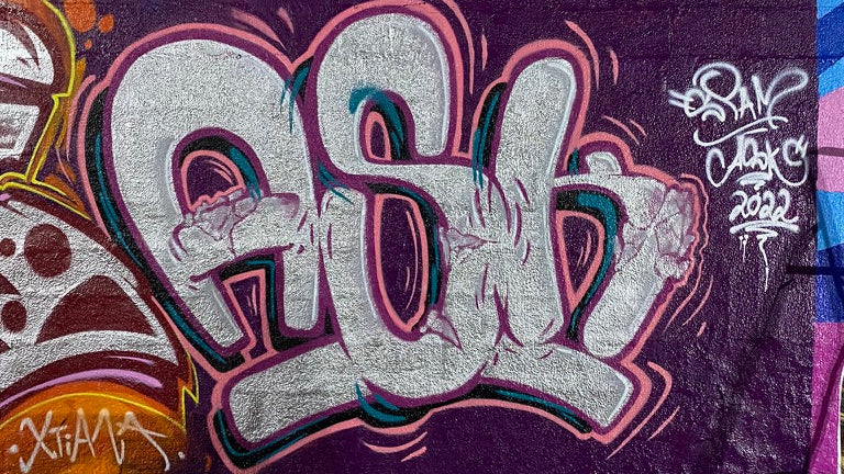 ASK Spam graffiti-style artwork on a wall with colorful text and designs.