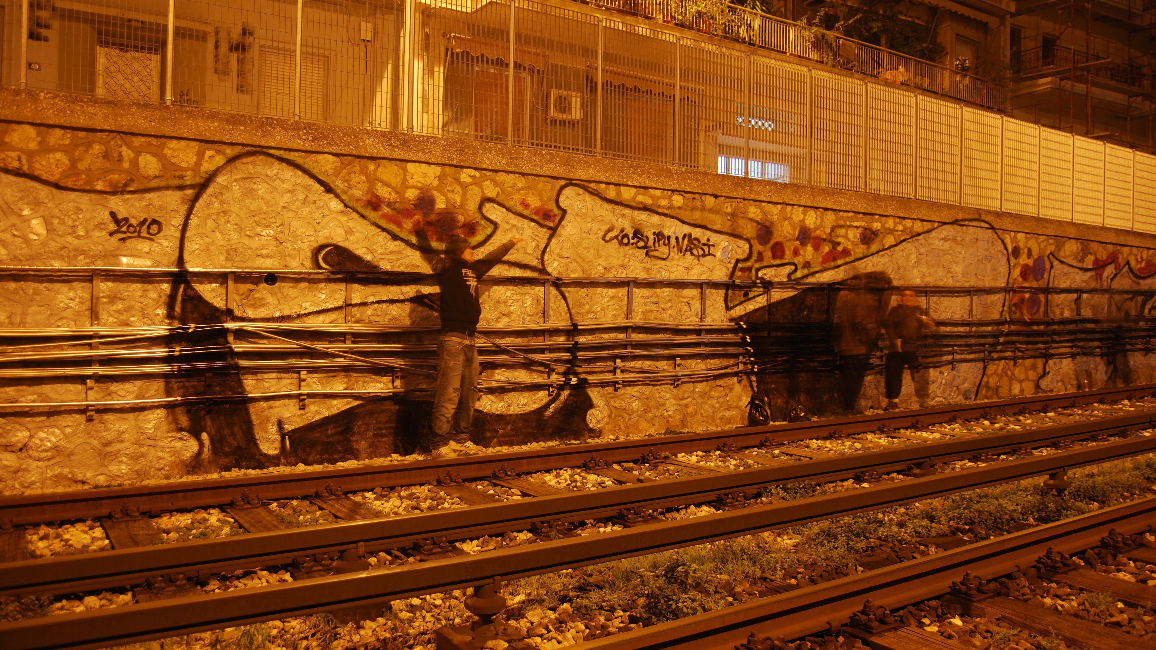 Graffiti on a wall near railway tracks at night