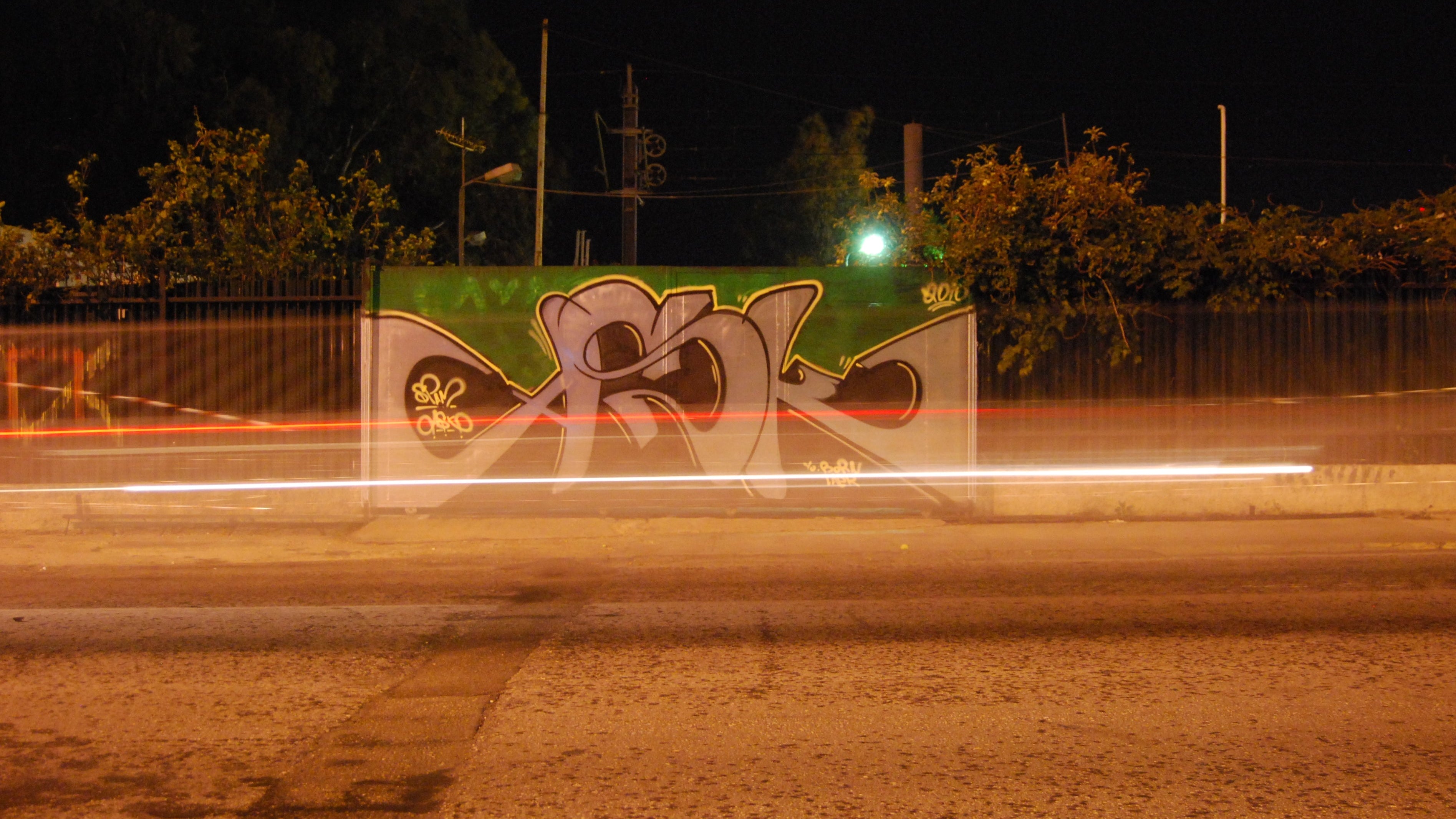 Graffiti on a wall with a road in the foreground at night